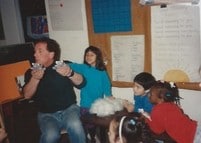 Four children play with an adult in a classroom