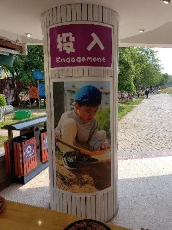 A pillar with an image of a small boy playing with dirt with a poster with the word 'Engagement'