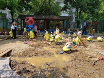 Children in yellow overalls playing in dirt