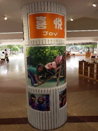 A pillar with children playing with a poser with the word 'Joy'