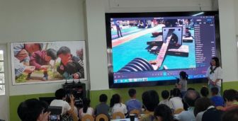 People sit in a large room watching a screen