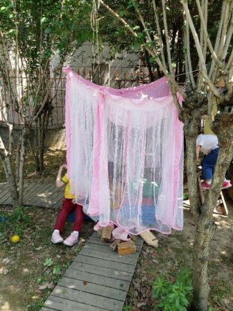 Children hide behind a pink sheet