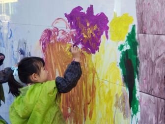 A child paints flowers on a wall