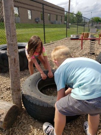 Two children place down a tire