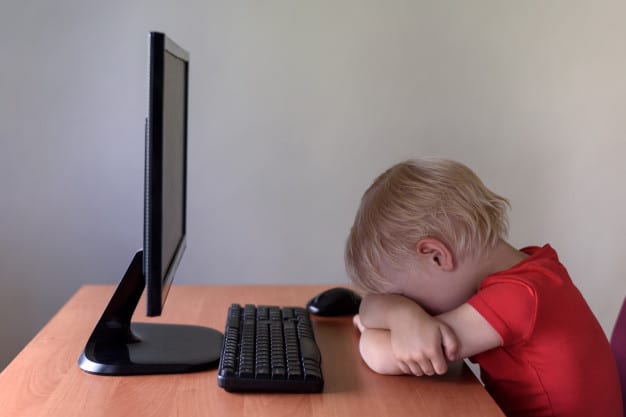 tired-little-blond-boy-sleeping-table-monitor_134398-2643