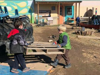 two young boys carrying wood material