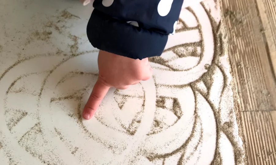 child drawing in sandbox