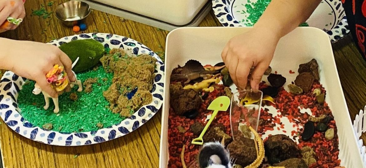 Children engaging in a sensory play activity with themed materials and toys on a table.